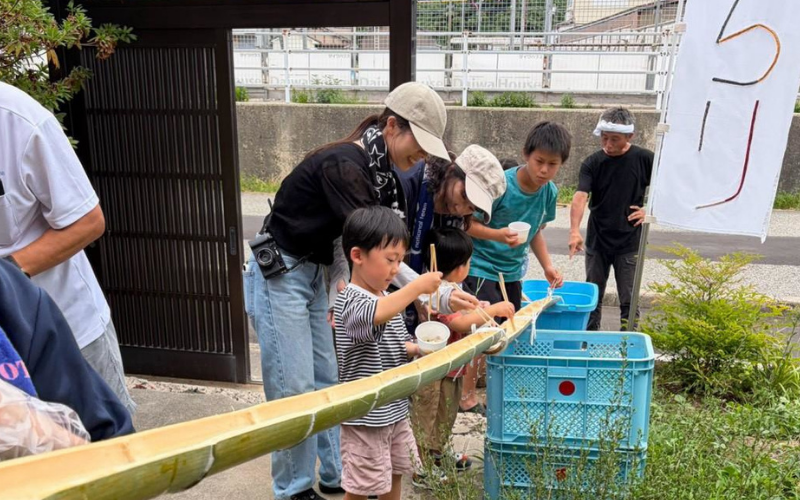 流しそうめんを手伝う大人と子どもたち